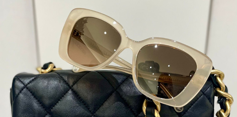 A pair of Chanel sunglasses on the top of a handbag.