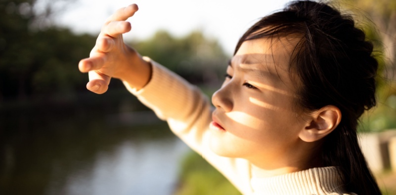 Child blocking sunlight with hand