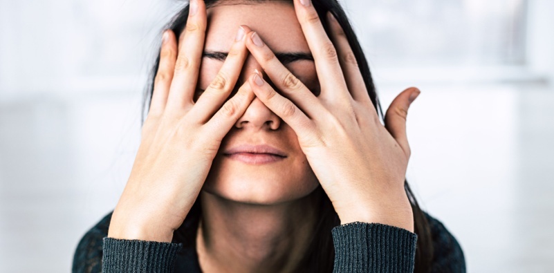 Woman covering her face with her hands, appearing tired or stressed