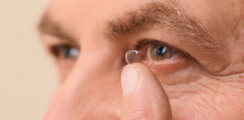 man holding a contact lens near his eye