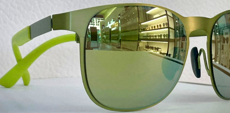 Close-up of green mirrored Porsche Design sunglasses highlighting luxury designer eyewear frames.]