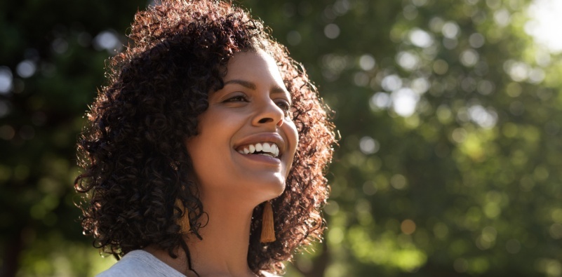 Smiling woman in nature with bright sunlight and greenery