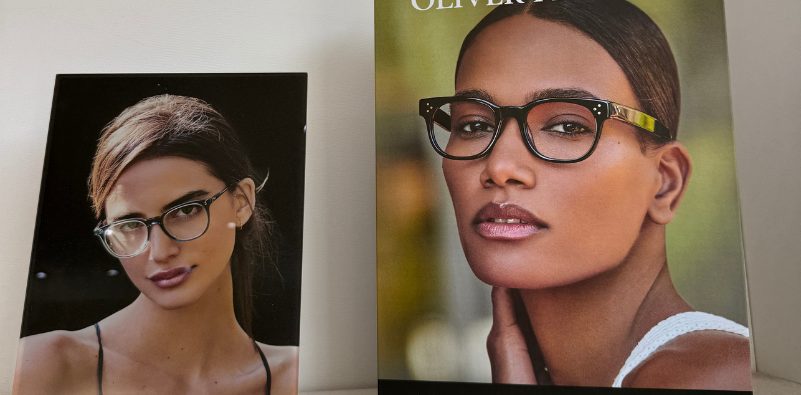 Oliver Peoples point of sale display cards featuring two women wearing Oliver Peoples glasses on a shelf at Optikal Opticians.