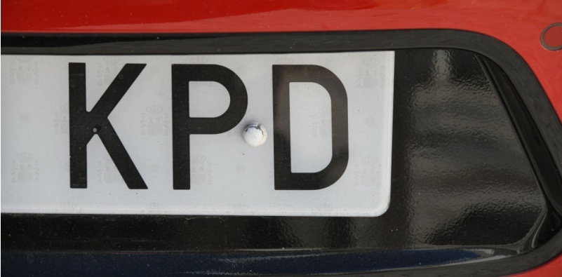 The back of a red car, showing a small portion of the number plate with the letters ‘KPD’ in black text on a white background.