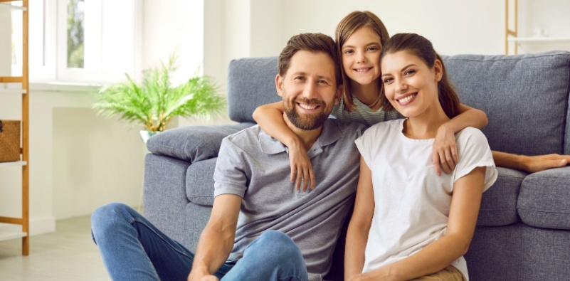 A cheerful, smiling family, sitting on the floor in the living room of their home