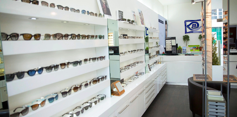 A photo of the inside of one of Optikal Opticians practices, showing a range of sunglasses and eyewear on white shelves