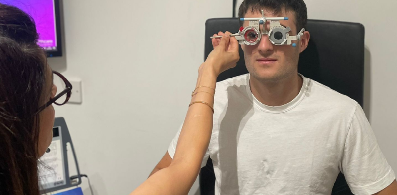 An optometrist testing a male patient’s vision with a trial frame