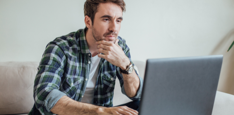 Man concentrating while working on a laptop at home