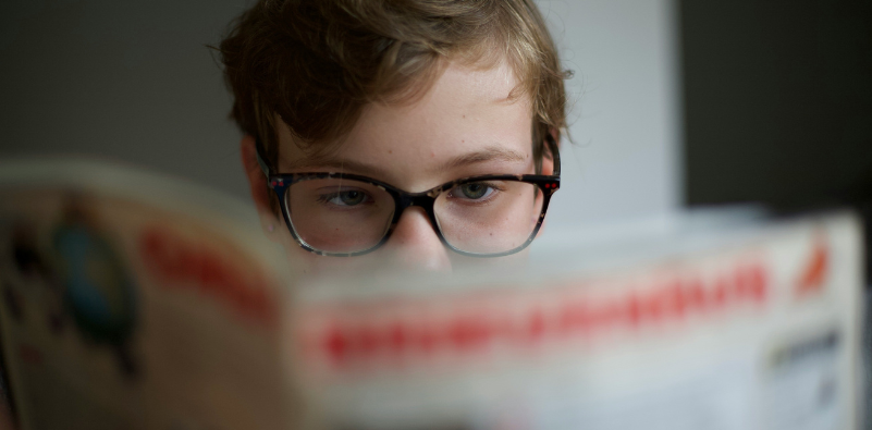 Child wearing glasses while reading a book